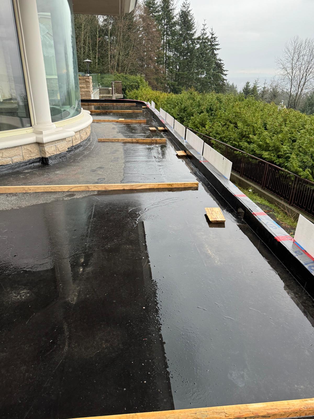 Elastomeric exterior wall coating being rolled onto commercial building exterior.